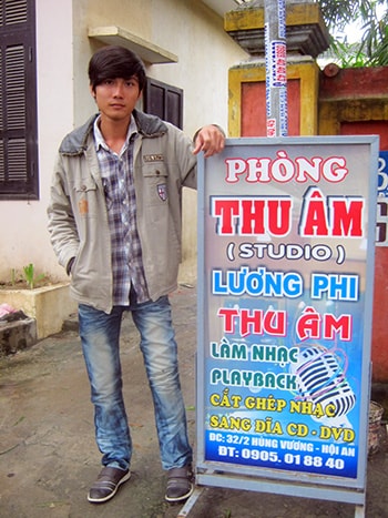 Lương Phi bên bảng hiệu phòng thu âm của mình.  Ảnh: THIÊN LÝ