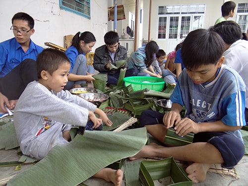 Các em nhỏ phụ anh chị gói bánh.