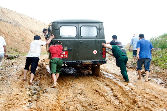 Anh em đoàn thanh niên tình nguyện  gồng lưng đẩy xe vượt đường lầy.