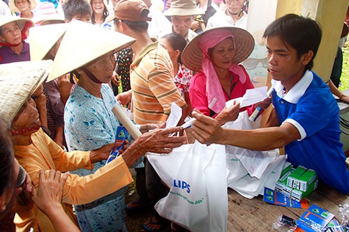 Thành viên đoàn tình nguyện “Thắp sáng vùng quê” cấp phát bóng đèn tiết kiệm điện cho người dân.