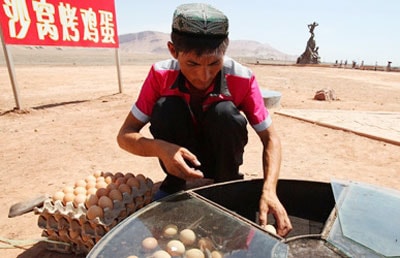 Một người dân tỉnh Tân Cương (Trung Quốc) luộc trứng dưới nhiệt độ cao ngoài trời. 