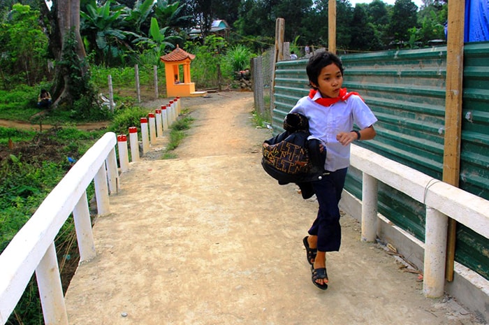 Một cậu bé chạy vội trên cây cầu mới tại thôn Vinh (xã Tà Pơơ, Nam Giang) để kịp giờ học. Ảnh: Lăng A Cúi