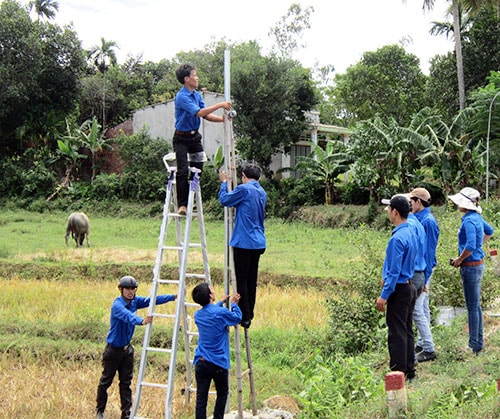 Các bạn đoàn viên, thanh niên tham gia giúp dân Tiên Sơn bắt đèn chiếu sáng dọc tuyến đường về trung tâm xã. Ảnh: N.H