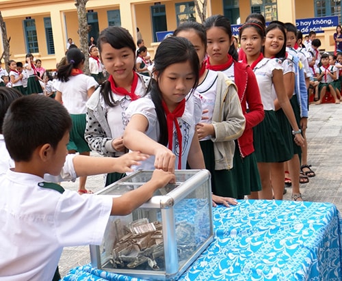 Học sinh trường Tiểu học Kim Đồng đóng góp quỹ “Giúp bạn đến trường” tại buổi lễ phát động. Ảnh: NGHIÊM AN