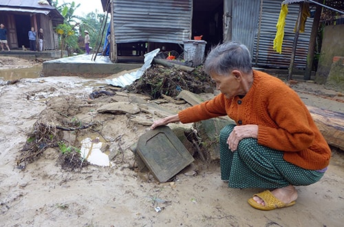 Bà Trần Thị Thí (82 tuổi, thôn Đại Mỹ, xã Đại Hưng) bên ngôi mộ trong vườn nhà bị lũ cuốn trôi.