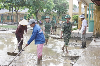 Bộ đội cùng bà con xã Đại Nghĩa dọn vệ sinh trường lớp sau lũ.   Ảnh: T.TRANG