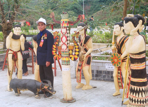 Nghệ nhân Cơlâu Bh’lao bên các tác phẩm điêu khắc đoạt giải B tại “Trại sáng tác” nhân kỷ niệm 10 năm ngày thành lập huyện Tây Giang.