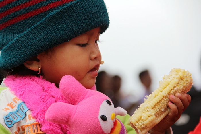 Children happily enjoy corncob.