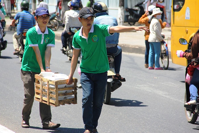 Hai tình nguyện viên đội nắng “tiếp tế” phần cơm cho các thí sinh trước cổng trường ĐH Quảng Nam.