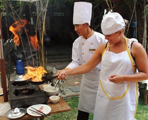 A tourist is guided to make Banh xeo (rice pancakes)