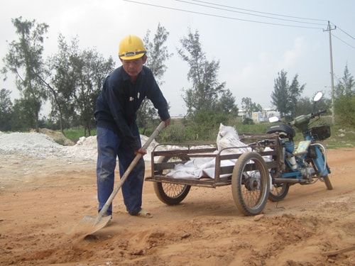 Ông Phạm Thế Mỹ xúc cát để chuẩn bị cho công việc đắp đường.Ảnh: V.T.N.T