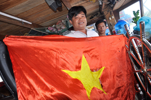 Ngư dân Huỳnh Ngọc Tuấn cùng lá cờ sẽ được gìn giữ cho thế hệ sau. Ảnh: Nguyễn Thành