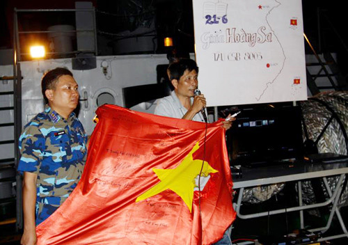 Nhà báo Trần Tuấn nhận lá cờ Tổ quốc của tàu CSB 4032 ở vùng biển Hoàng Sa.  Ảnh: Mạnh Thường
