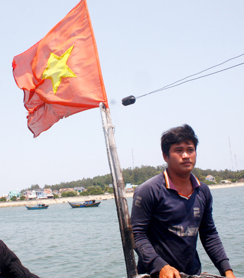 Ngư dân dũng cảm Bùi Văn Phải và lá cờ được bảo vệ ở Hoàng Sa. Ảnh: Nguyễn Thành