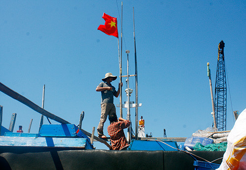 Ngư dân Núi Thành cột chặt dây cờ chuẩn bị cho chuyến đánh bắt khơi xa, góp phần bảo vệ chủ quyền biển đảo Việt Nam.  Ảnh: NGUYỄN THÀNH