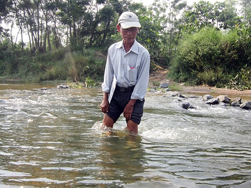 Trưởng thôn Cẩm La - Phạm Ước băng sông suối đi họp ở xã.  Ảnh D.T