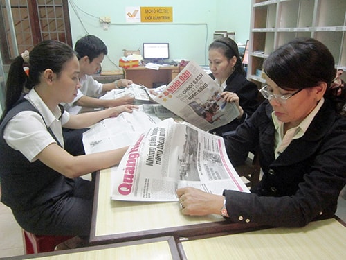 Cán bộ và nhân đọc báo Đảng tại Bưu điện Sơn Hiệp (thị trấn Đông Phú, Quế Sơn)