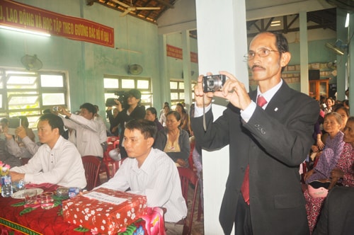 Ông Hồ Kim Cảm đang quay phim tư liệu bằng máy ảnh mi ni tại ngày hội kết đoàn của thôn.  Ảnh: H.GIANG