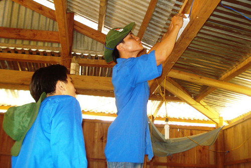 Đoàn viên thanh niên Trường CĐ Kinh tế - kỹ thuật Quảng Nam tình nguyện giúp dân bắt bóng điện tại xã A Nông (Tây Giang). Ảnh: V.A