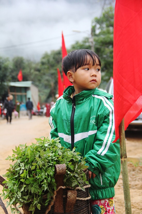 Một em bé Cơ Tu hồn nhiên theo mẹ ra chợ bán rau rừng.