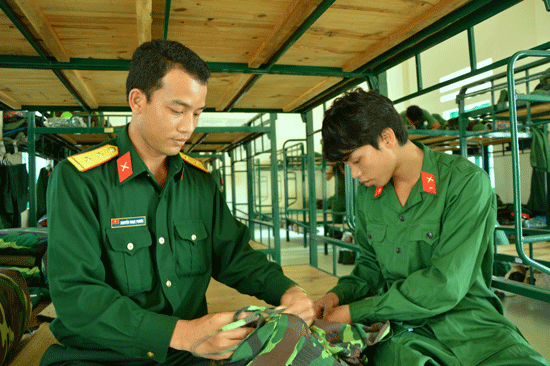 Cán bộ huấn luyện của đơn vị giúp thanh niên sắp xếp quân tư trang.