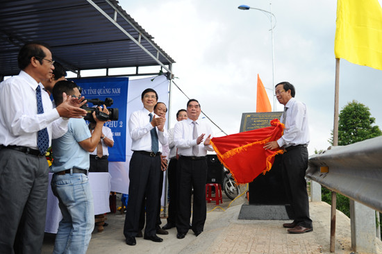 Các đồng chí lãnh đạo trung ương và tỉnh thực hiện nghi thức gắn biển công trình chào mừng 40 năm giải phóng Quảng Nam tại cầu Kỳ Phú 1. Ảnh: MINH HẢI