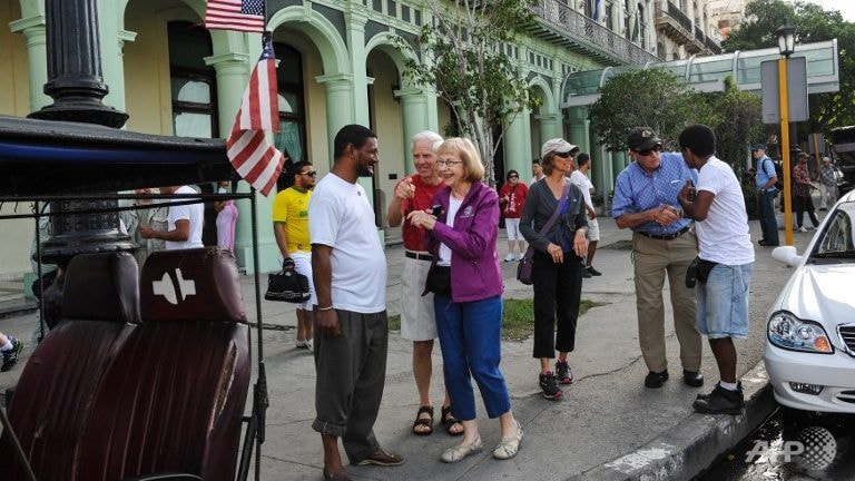 Khách du lịch cầm cờ Mỹ trên đường phố Havana.  Ảnh: AFP