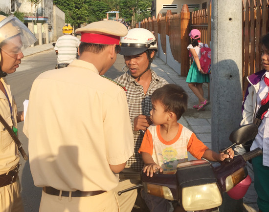 Cảnh sát giao thông Nam Giang tuyên truyền cho phụ huynh về quy định đội MBH với trẻ em. Ảnh: SC