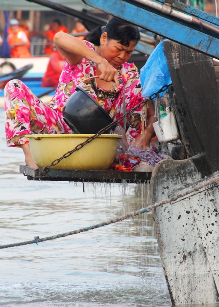 Ở chợ nổi, mọi sinh hoạt của người dân cũng đều diễn ra trên ghe, xuồng. Như người phụ nữ này, tranh thủ sau khi bán hàng, lại tất bật cho công việc giặt giũ áo quần trên mép ghe gia đình.