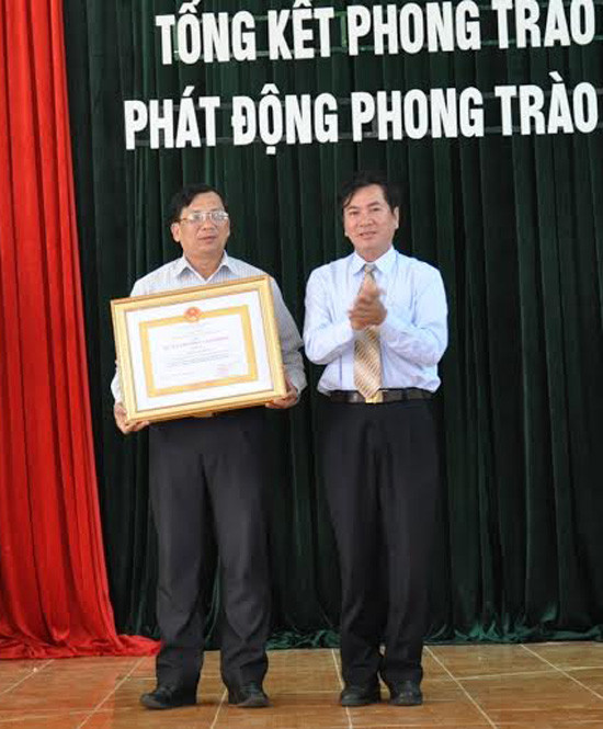 Thừa ủy nhiệm Chủ tịch nước, Phó trưởng Ban thi đua khen thưởng tỉnh Nguyễn Đình Tăng trao Huân chương Lao động hạng Ba cho ông Nguyễn Văn Dõng (bên trái).
