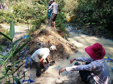 Tổ công tác đang lấp lại hồ chứa nước đào trái phép trong rừng phòng hộ Sông Tranh. Ảnh do Sở Tài nguyên - môi trường cung cấp.