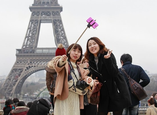 Du khách dùng gậy chụp ảnh selfie tại Tháp Eiffel (Pháp).