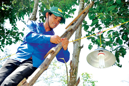 Lắp bóng điện “Thắp sáng đường quê” cho nhân dân thôn Ban Mai 2, xã Ba. Ảnh: VINH ANH