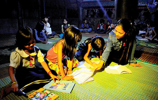 Blướch Thị Bloó (thôn Blừa) dạy các em nhỏ học ở gươl thôn A Rớh. Ảnh: XUÂN KHÁNH