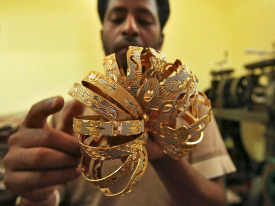 Một nhân viên công ty kim hoàn tại Ấn Độ đang kiểm tra số lượng vàng.
