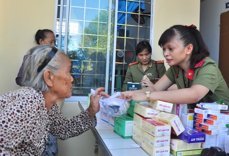 Nữ chiến sỹ Công an nhân dân phát thuốc cho người dân. Ảnh: VINH ANH