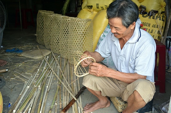 Ông Trần Nhớ tranh thủ đan lờ để kịp giao cho khách.  Ảnh: QUỐC TUẤN