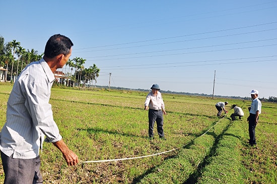 Cán bộ thôn Thạch Hưng, xã Tam Xuân 2 đo đạc diện tích đất đã dồn điền đổi thửa. Ảnh: VINH ANH