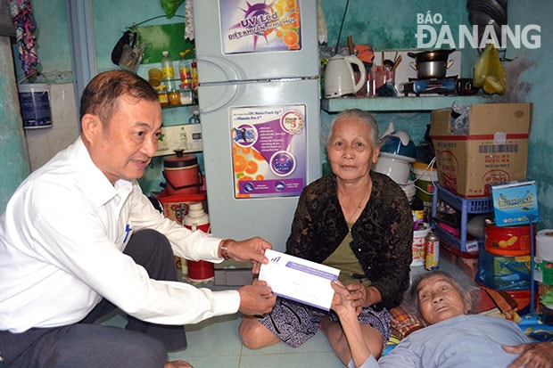 Đại diện Tổng Công ty CP Dệt may Hòa Thọ trao tiền hỗ trợ cho bà Trần Thị Anh (người đang nằm)