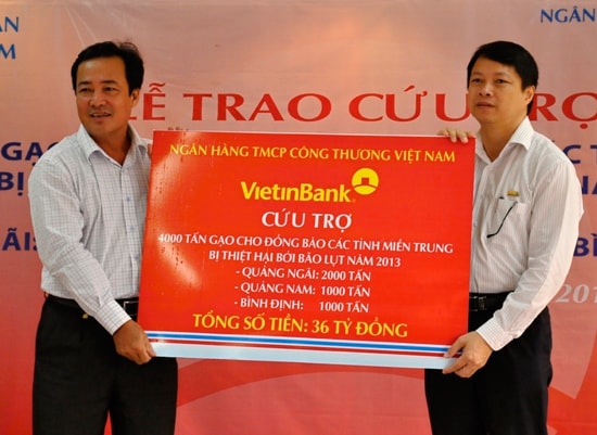 Phó Chủ tịch Thường trực UBND tỉnh Huỳnh Khánh Toàn (bên trái) tiếp nhận tấm biểu trưng ủng hộ 1.000 tấn gạo cho đồng bào lũ lụt từ đại diện VietinBank. 