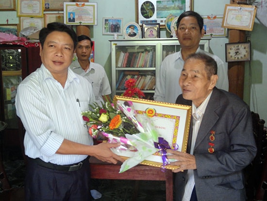 Phó Bí thư Huyện ủy Phú Ninh - Bùi Võ Quảng trao Huy hiệu 70 năm tuổi Đảng cho ông Vũ Minh Tuân.