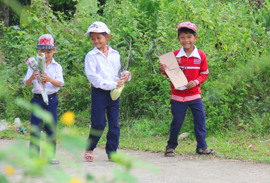 Những học sinh vùng cao cầm bó hoa rừng đến trường, mừng ngày vui của thầy cô giáo.