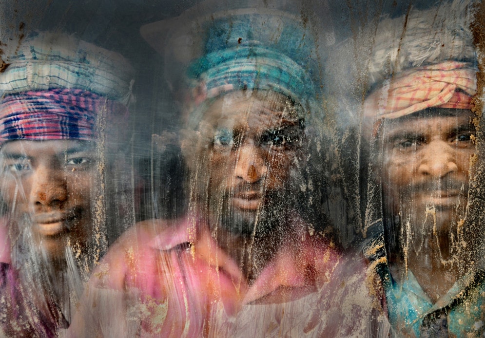 A gravel crushing workplace remains full of dust and sand. Three gravel workmen are looking through the window glass. #  © Faisal Azim 