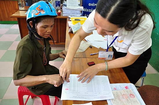 Nhân viên bưu điện hướng dẫn người có công điểm chỉ khi nhận chế độ. Ảnh: V.ANH