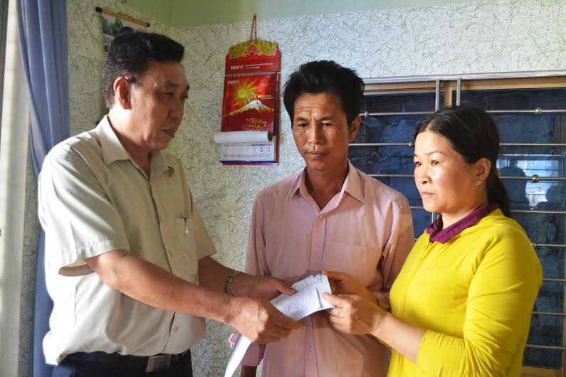 Ông Huỳnh Bá Thanh trao số tiền bảo hiểm 69 triệu đồng cho gia đình ngư dân Võ Quang Thái. Ảnh: Q.V