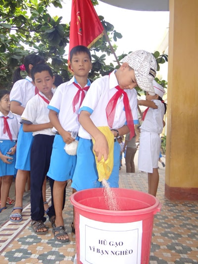 Đội viên tham gia phong trào “Hũ gạo vì bạn nghèo”.  Ảnh: TH.NGÂN