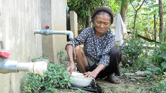 Hàng ngày cụ bà Bùi Thị Lai vẫn dùng chung nguồn nước nhiễm phèn từ nhà hàng xóm đưa về. Ảnh: Dung Thùy