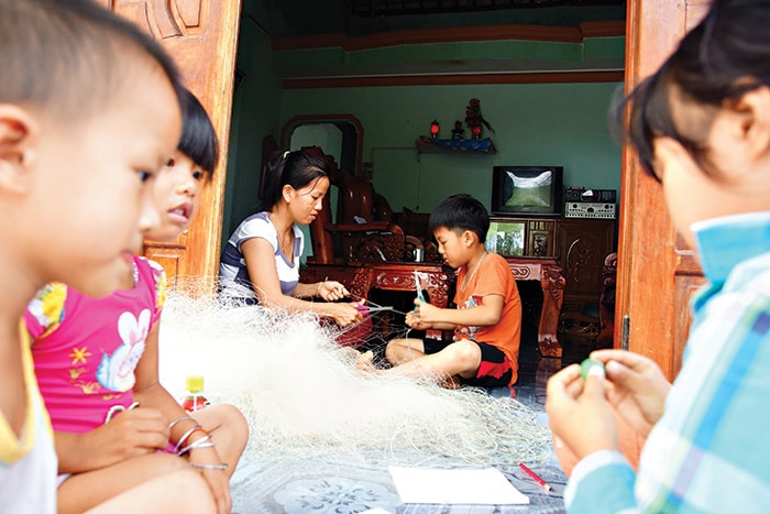 Em Trần Hoàng Nguyên, thôn Kỳ Trân, xã Bình Hải - Thăng Bình giúp mẹ vá lưới chuẩn bị cho chuyến biển của cha.