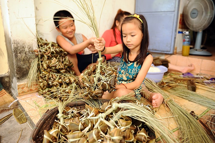 Trẻ em nghỉ hè phụ giúp gói bánh.