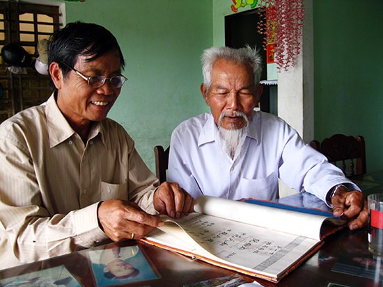 Các ông Nguyễn Phước Hùng (trái), Lê Văn Khóa đọc lại Gia phả tộc Nguyễn làng Uất Lũy.Ảnh: V.T.L